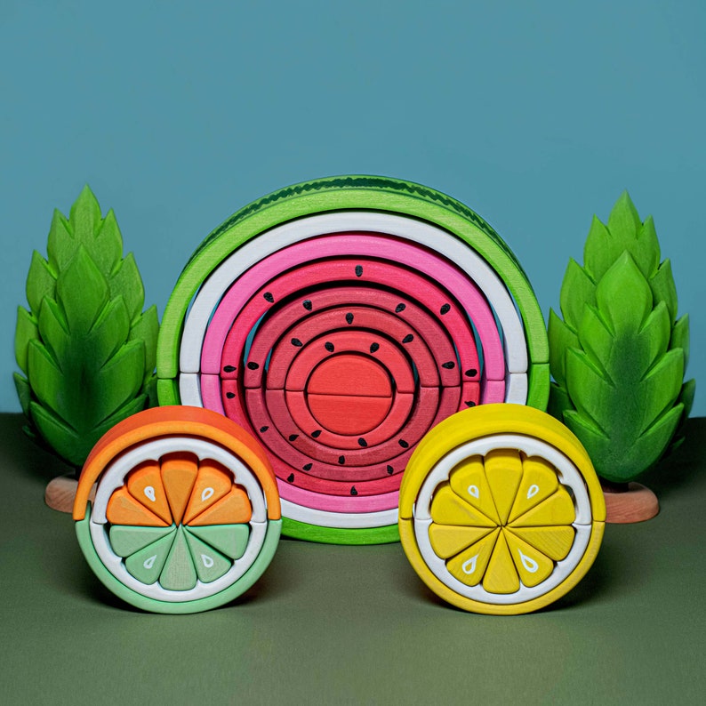Set of Montessori-inspired wooden stacking toys including watermelon on a green background, interactive and educational.
