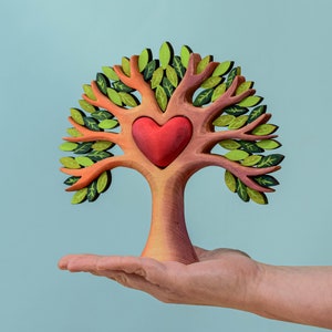 Waldorf inspired heart tree toy cradled in an adult's hand, showcasing the craftsmanship and size of the wooden toy