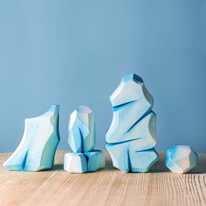 Geometric wooden ice structures with varying heights displayed on a wooden table with a blue backdrop.