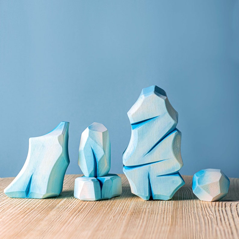 Geometric wooden ice structures with varying heights displayed on a wooden table with a blue backdrop.