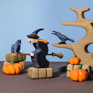 Storytelling setup with a wooden cat figure, witch, and crow in front of a wooden tree, ideal for creative Montessori playtime.