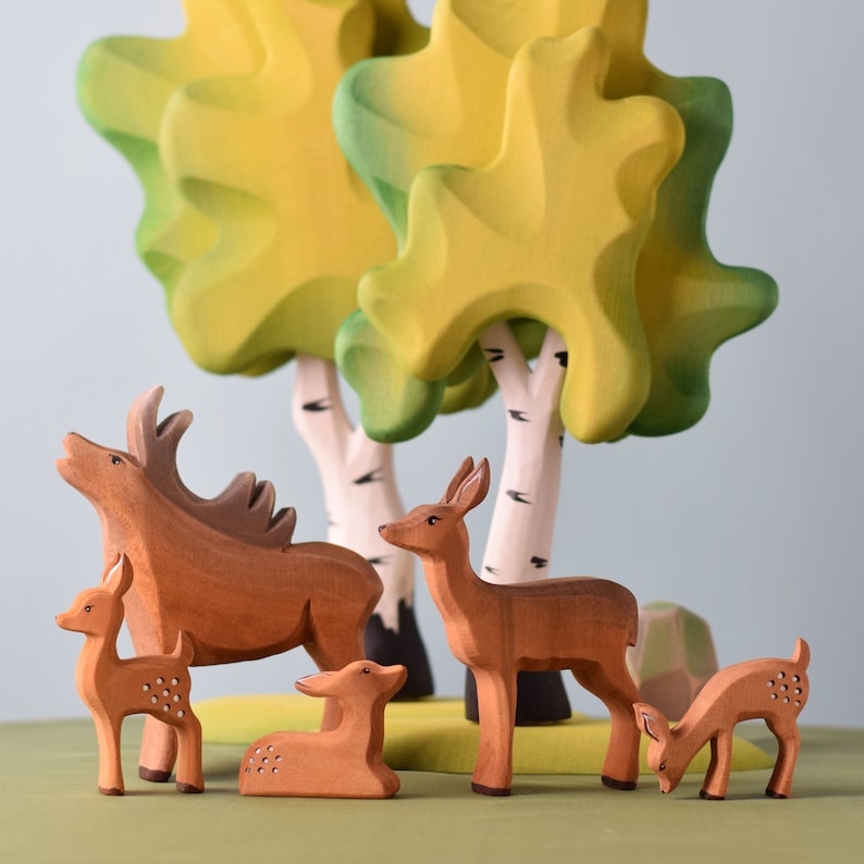Woodland serenity: handcrafted wooden deer family in a tranquil forest clearing, a unique handmade gift.