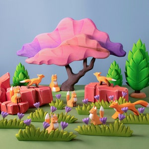 Vibrant wooden playset featuring foxes in a colorful forest with a large purple and pink tree and green bushes on a gray surface.