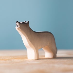 Close-up of a wooden wolf figurine howling on a wooden surface.