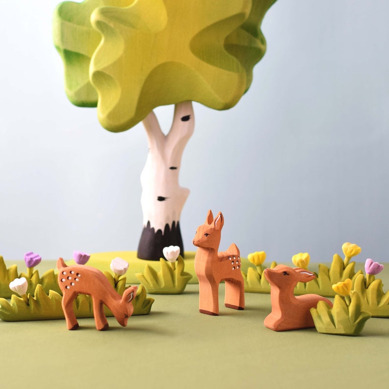 A set of wooden toy figures depicting forest animals, like deer and foxes, with intricate details and smooth finishes.