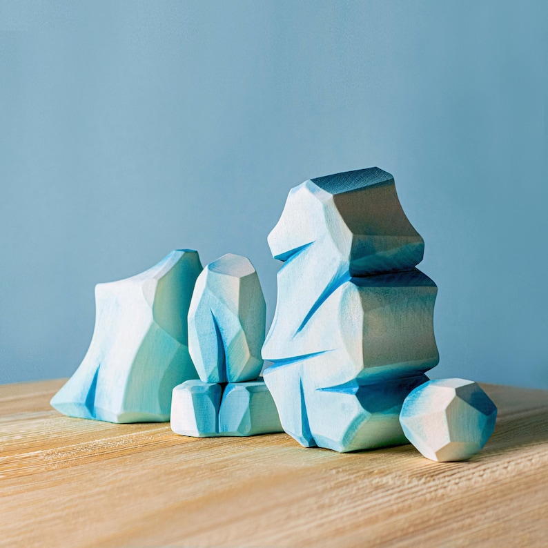 Set of abstract wooden ice formations in various sizes on a light wooden surface against a soft blue background.