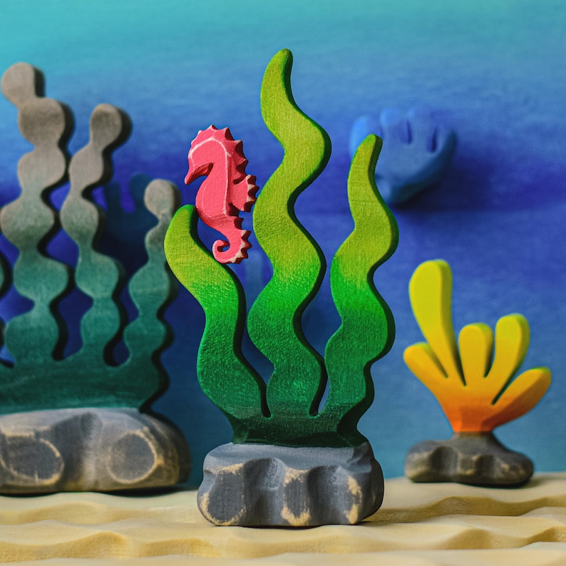 An ensemble of sea flora and fauna with a pink wooden seahorse figurine as the centerpiece, set against a blue oceanic background.