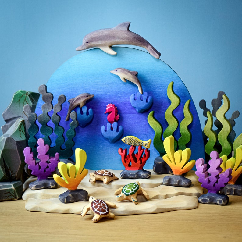 A comprehensive ocean display with a pink wooden seahorse, dolphins, turtles, and colorful marine life, all crafted in wood and arranged against a circular blue backdrop.
