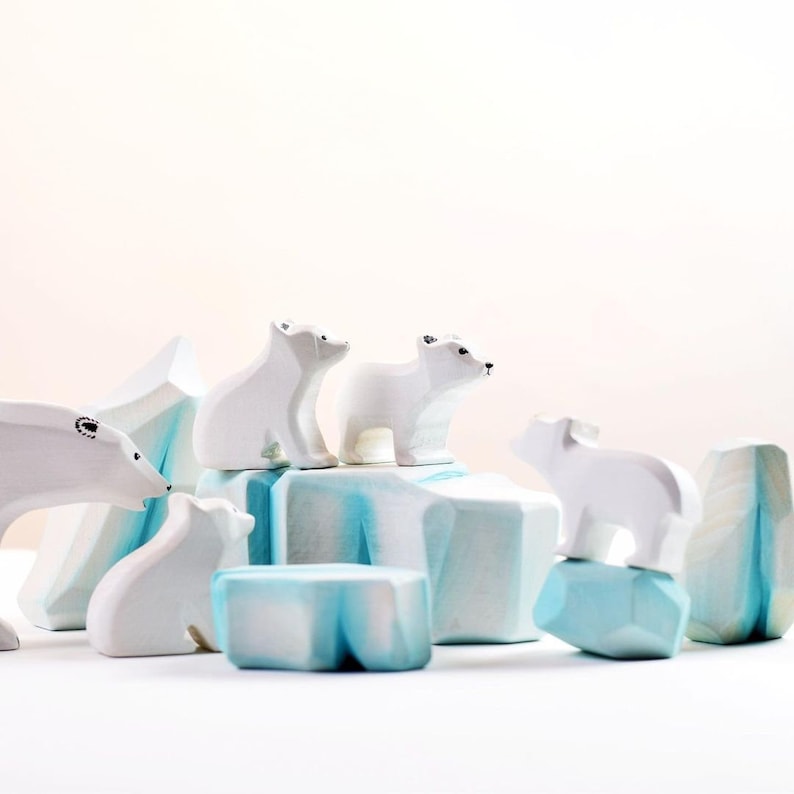 White wooden polar bear figures on abstract blue ice blocks with a soft beige background.