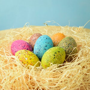 Peut inclure: Un nid d'œufs de Pâques colorés et mouchetés dans des tons de rose, bleu, vert, jaune et marron. Les œufs sont nichés dans un lit de paille.