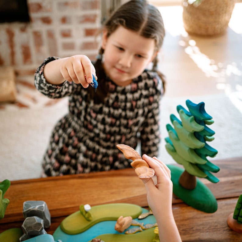 Young girl engaging in play with a wooden kingfisher toy, demonstrating BumbuToys’ focus on interactive and educational toys that inspire creativity and a connection with nature.