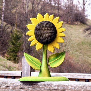 Handmade sustainable sunflower Waldorf toy positioned outdoors with natural background enhancing its vibrant colors