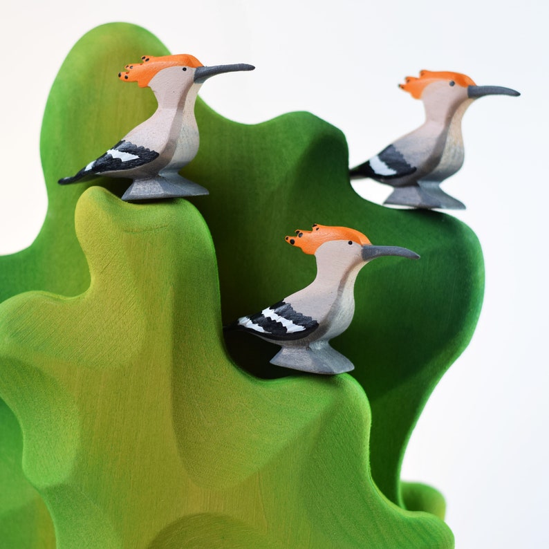 a group of wood birds on a green plant
