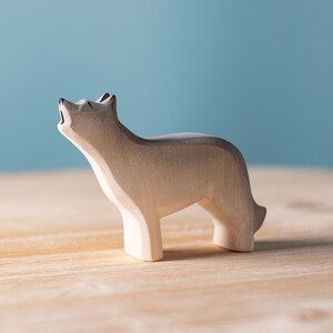Wooden figurine of a howling wolf on a wooden surface.