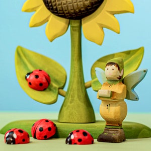 Sunflower wooden toy in a playful Waldorf setting with ladybug figures and a fairy, encouraging storytelling
