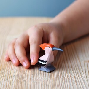 a hand holding a small bird