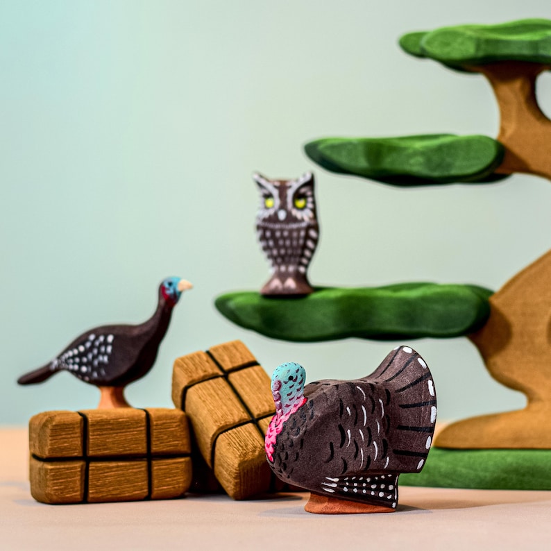 Wooden Turkey Hen Figurine near owl figure and green trees, Waldorf-inspired imaginative toy