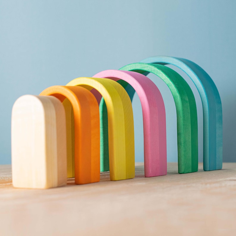 Array of arch-shaped pieces from the ARCADE collection rainbow stacker, encouraging problem-solving and imaginative play.