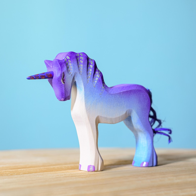 Purple tailed wooden unicorn toy on a table.