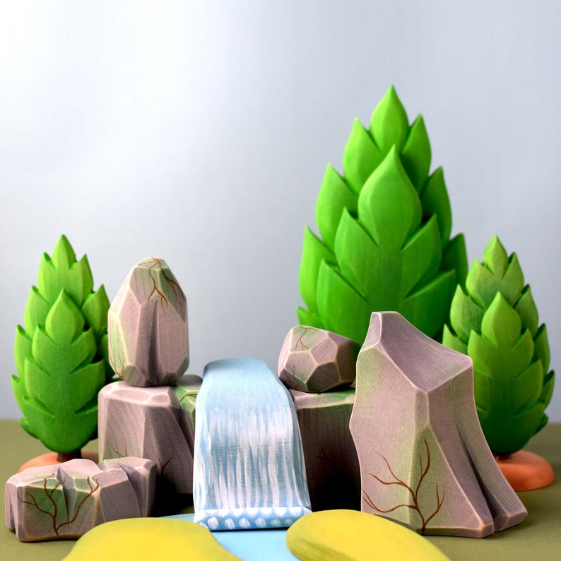 Eco-friendly wooden landscape figures for imaginative play, with details resembling a rocky terrain, a flowing waterfall, and lush greenery