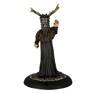 Può includere: Statuina in miniatura di una figura in abito nero, con un elmo di metallo con corna e un colletto di pelliccia. La figura è in piedi su una base circolare con una texture simile alla pietra, con una mano alzata in segno di saluto.