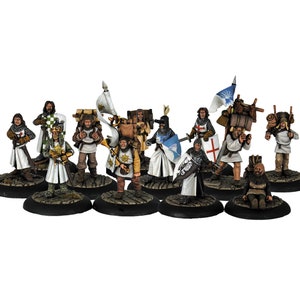 May include: A group of miniature medieval figures, including knights and porters, are displayed. The figures are painted with detailed armour, shields, and weaponry. Some figures carry flags and supplies, while others hold swords. The figures are on a white background.