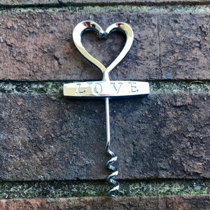 May include: Silver heart-shaped corkscrew with the word "LOVE" engraved on the handle.