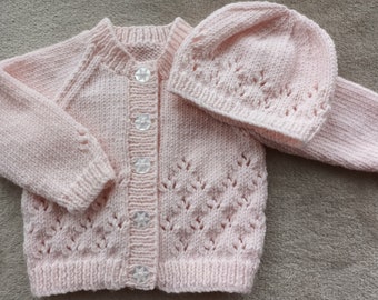 Newborn baby girls cardigan and hat hand-knitted in a soft smooth pale pink/ peach