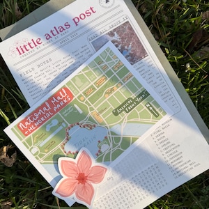 May include: A collection of paper ephemera, including a map of the National Mall, a newspaper-style newsletter, and a floral sticker. The map highlights Tidal Basin and surrounding memorials. The newsletter is titled "little atlas post."