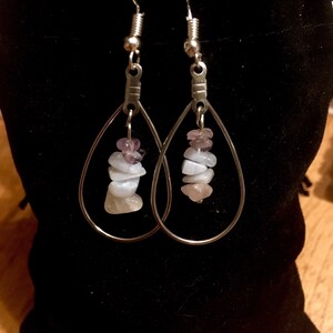 Peut inclure: Une paire de boucles d'oreilles en argent en forme de larme avec une pile de petites pierres bleu clair, rose et violettes suspendues à chaque boucle d'oreille.