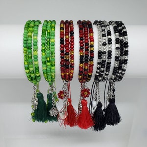 May include: Six beaded bracelets with tassel charms. The bracelets are green, red, and black. The tassels are green, red, and black.