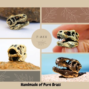 May include: Four close-up images of a gold-colored T-Rex dinosaur skull charm. The charm is made of brass and has a detailed design. The text "T-REX" is visible in the image. The text "Handmade of Pure Brass" is also visible in the image.