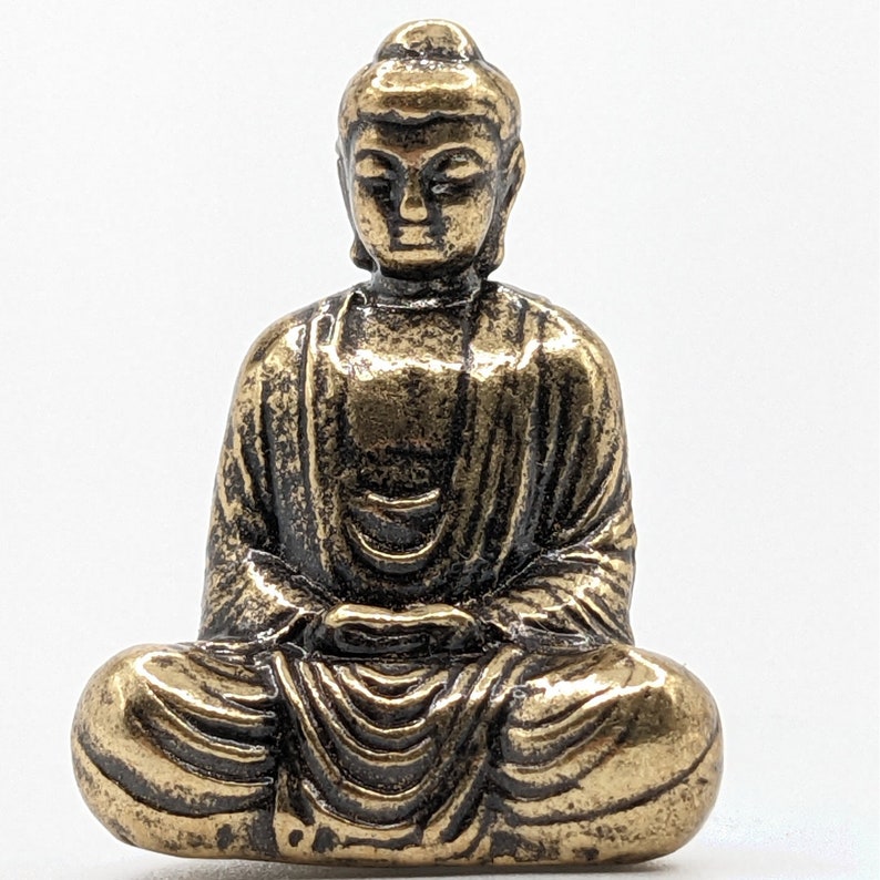 May include: A small gold-colored metal statue of Buddha sitting in a meditative pose.