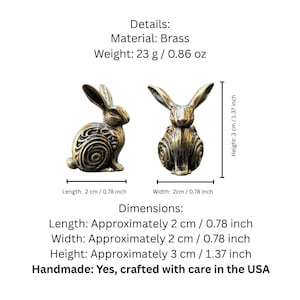 May include: Two small brass rabbit figurines. Each rabbit is about 2 inches wide and 3 inches tall. The rabbits are detailed with a swirling pattern on their bodies. The rabbits are handmade in the USA.