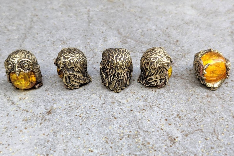 May include: Five small brass owl figurines with amber glass eyes. The owls are facing different directions.