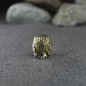 May include: A gold-colored metal thimble with an intricate design of leaves and branches.