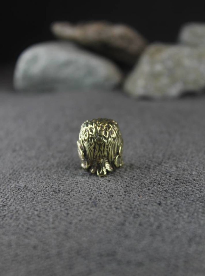 May include: A gold-colored metal thimble with an intricate design of leaves and branches.