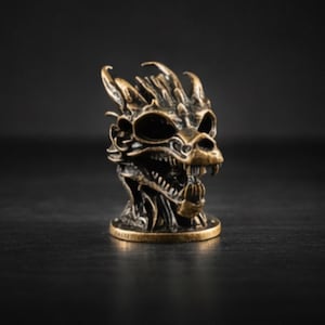 May include: A bronze-colored dragon skull figurine with intricate details. The sculpture features sharp teeth, large eye sockets, and textured scales. The dragon's head is mounted on a circular base, showcasing a fantasy theme.