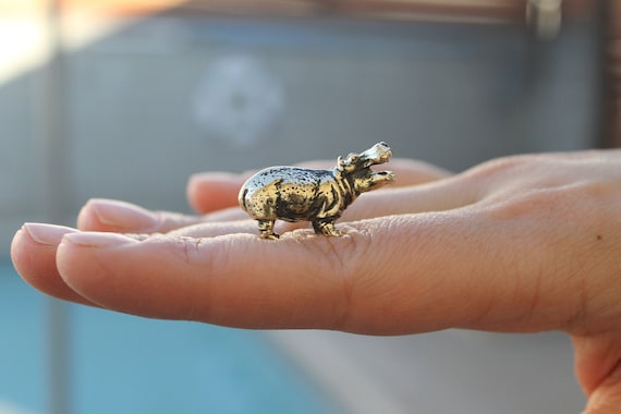 A tiny solid brass hippo figurine with 1,687 favorites — handmade miniature animal sculpture that's clearly become a cult collectible for a reason.