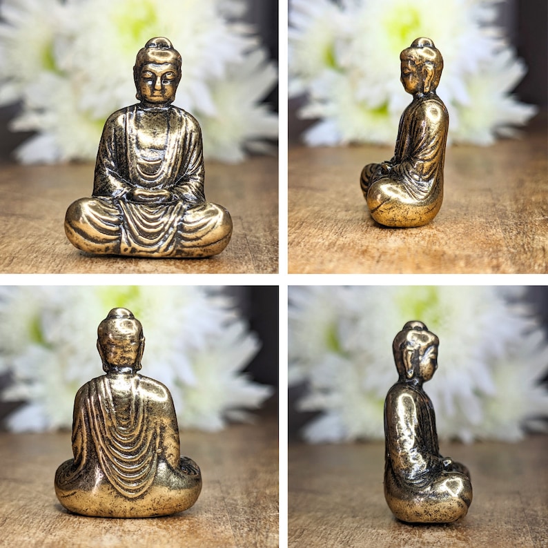 May include: A small, gold-colored, metal statue of a seated Buddha. The statue is in a meditative pose with hands resting in the lap. The statue is about 2 inches tall.