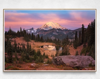May include: A mountain peak with snow-capped summit reflected in a still lake, surrounded by evergreen trees and a pink and purple sunset sky.