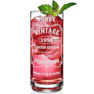May include: A highball glass filled with a pink drink and ice, decorated with mint leaves. The glass is engraved with the words "Trudy Vintage 1954 Limited Edition Aged to Perfection Happy 70th Birthday."