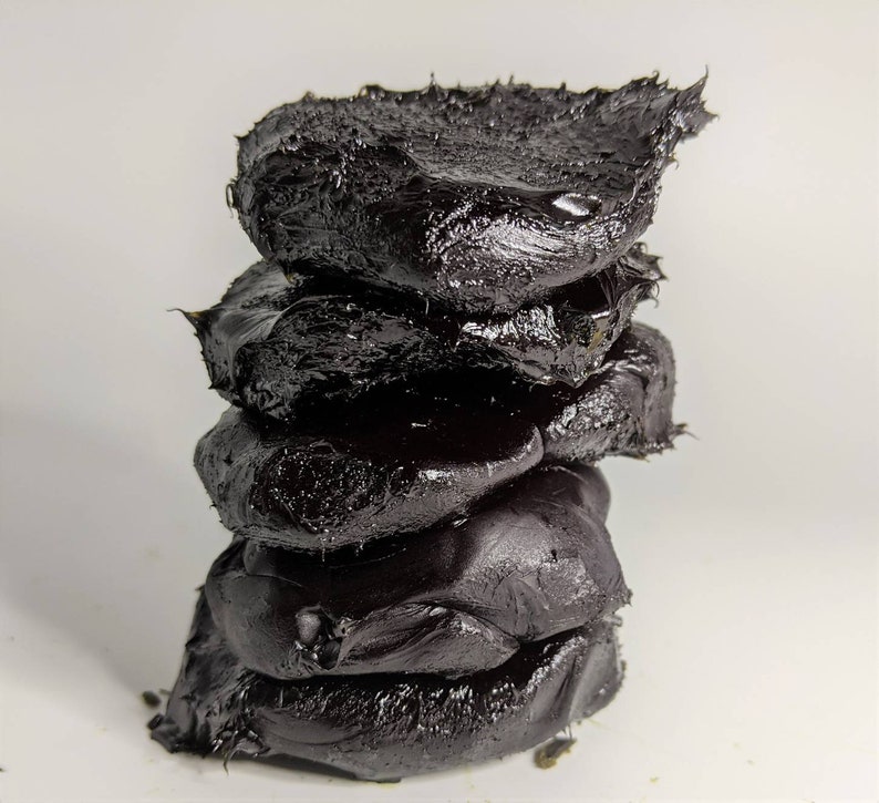 May include: A stack of four black, irregularly shaped, sticky, and gooey pieces of tar or asphalt.