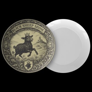 May include: A round decorative plate with a black and gold illustration of a black sheep wearing a crown, with the text "BLACK SHEEP SHINE FUEL-UP & FROLIC". A white plate is next to it.
