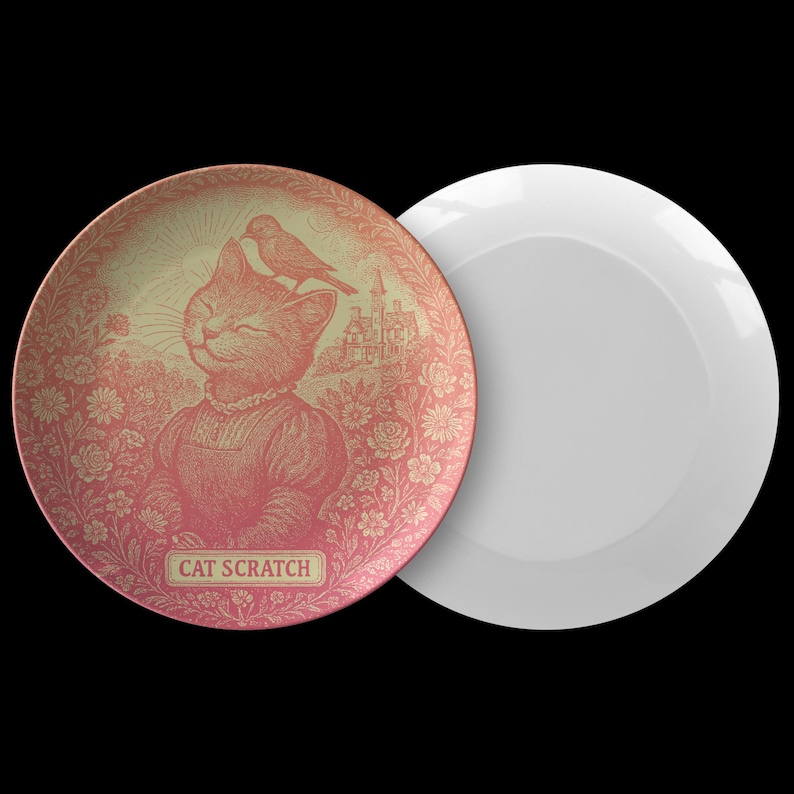 May include: Two decorative plates. One plate features a pink and gold illustration of a cat with a bird on its head, surrounded by flowers and a castle. The text "CAT SCRATCH" is below the cat. The other plate is plain white.