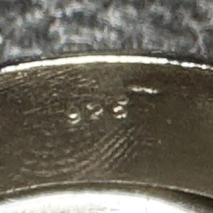 Pode incluir: Close-up de um anel de prata com a inscri&ccedil;&atilde;o "925" na banda interna.