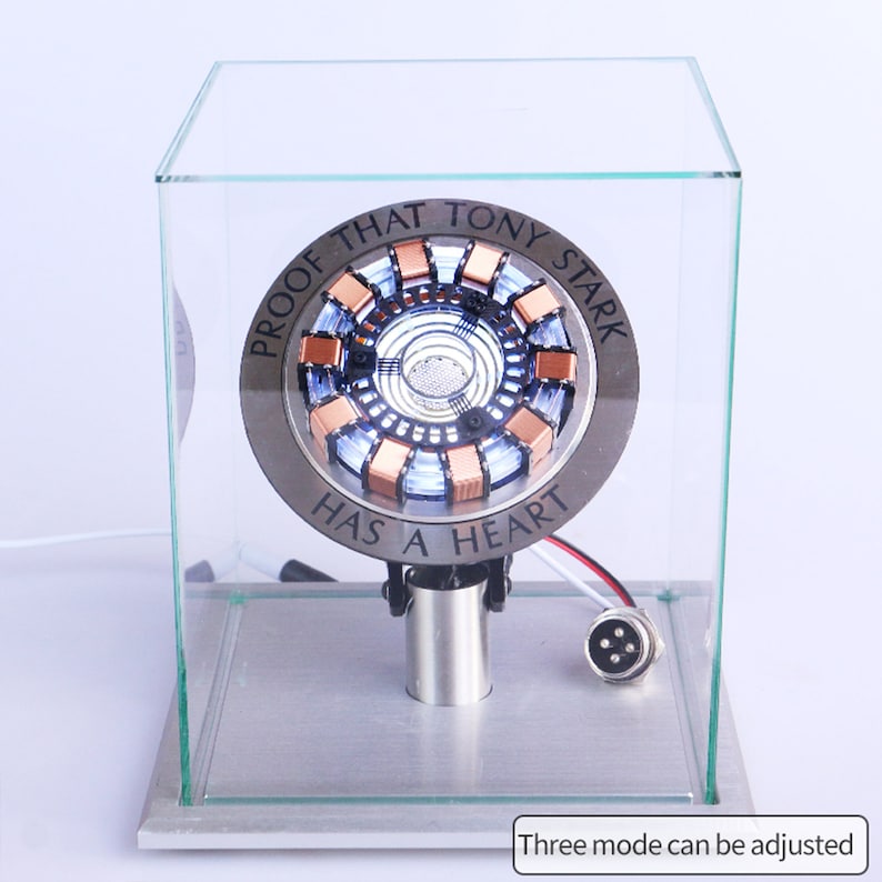 May include: A glass display case with a silver and copper-colored Iron Man Arc Reactor replica inside. The replica has a white light and the text "Proof that Tony Stark has a heart".