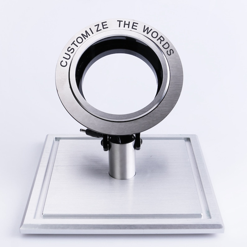 May include: A silver ring with the words "Customize the Words" engraved around the outside. The ring is on a silver stand.