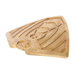 May include: A gold-colored shield with a star and other decorative elements. The shield is made of a textured material and has a slightly curved shape.