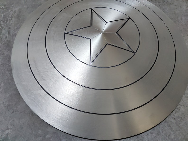 May include: A silver metal shield with a five-pointed star in the center. The shield has concentric circles around the star.